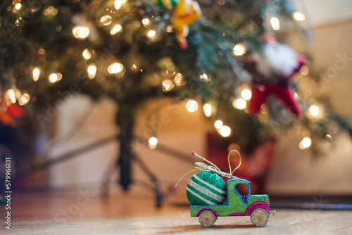 Close-up of decorations on hardwood floor against illuminated Christmas tree at home photo