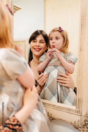 a cute little girl in a plaid dress and mom primping.