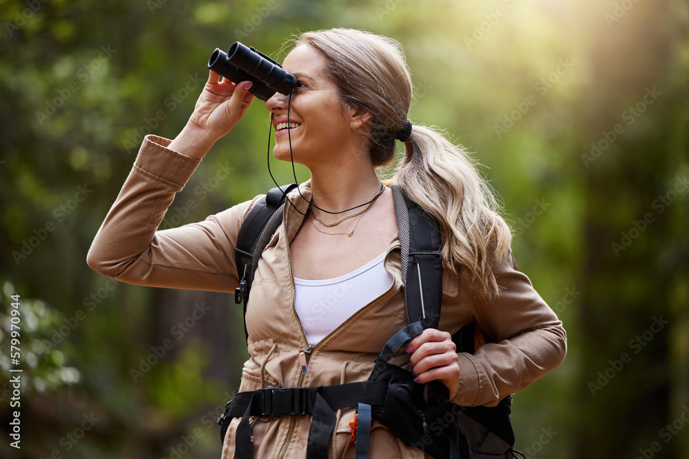 Obraz premium Binoculars, forest and hiking woman for travel journey, jungle adventure and nature explore with backpack and gear. Happy hiker or camper person trekking in woods and search or birdwatching outdoor