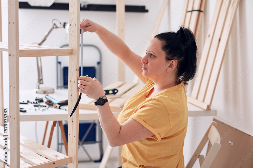 Woman assembling new wooden shelf and furniture in the apartment. Woman assembling new wooden shelf and furniture in the apartment.