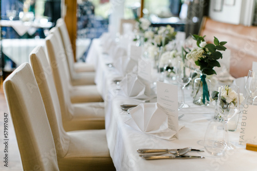 Edler Hochzeitstisch mit weißen Stuhlhussen bei Hochzeitsfeier im Restaurant