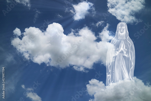 Mary praying in white clouds with light ray from heaven. religion,
