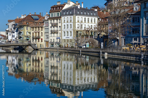 Scenic view of Aare River with boardwalk and cityscape of Swiss City of Thun on a sunny winter day. Photo taken February 21st, 2023, Thun, Switzerland.
