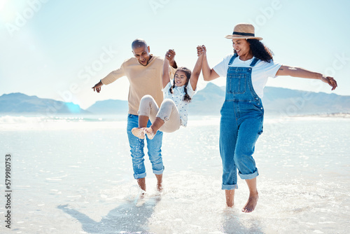 Mother, father and girl play on beach for bonding, quality time and summer adventure together in water. Travel, freedom and happy mom, dad and child enjoy holiday, vacation and relax on weekend #579980753
