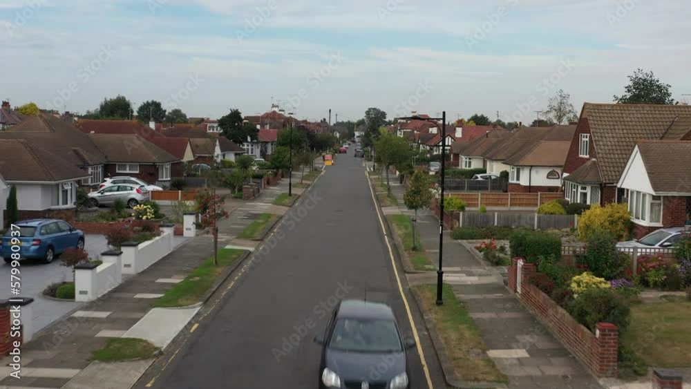 Black car passing on empty road in United Kingdom neighborhood Black car passing on empty road in United Kingdom neighborhood