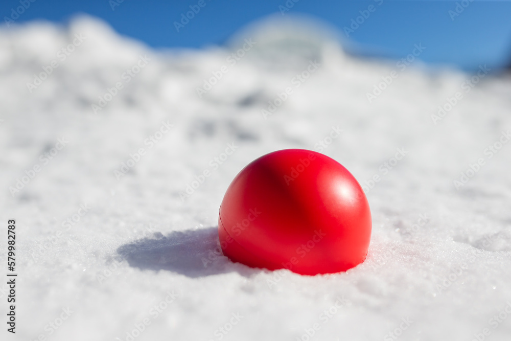 Red ball merged in white snow with blue background. Conceptual art about the world an critical time / global warming Red ball merged in white snow with blue background. Conceptual art about the world an critical time / global warming
