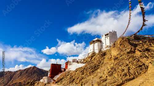 Panorama winter landscape of Leh palace with five color prayer flags blowing in the wind, Leh palace in the background.Tsemo Namgyal monastery in Ladakh,India.Blue sky with clouds.Himalayan range.