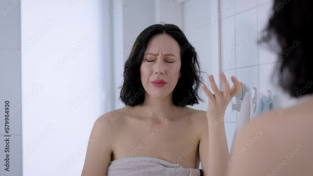 Upset middle aged woman looking at her wrinkles in bathroom mirror. Frustrated Upset middle aged woman looking at her wrinkles in bathroom mirror. Frustrated
