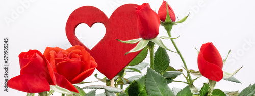 Detail of Red Roses in a floral arrangement with wooden heart, against a white background. Concept of love and Valentine's Day. Banner Header image.