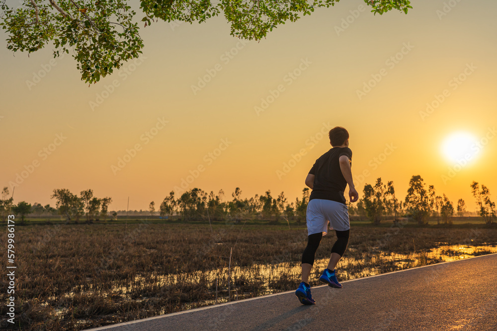 Young fitness asian man is running and jogging an outdoor workout on the road in the morning for lifestyle health.