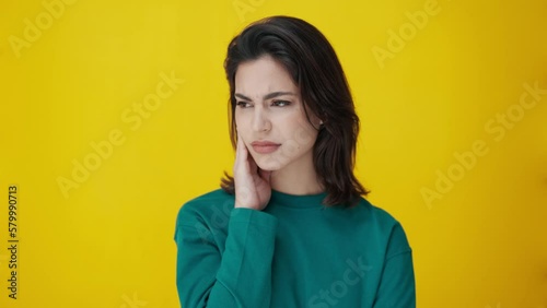 Video of beautiful woman with toothache touching her face on isolated on yellow photo