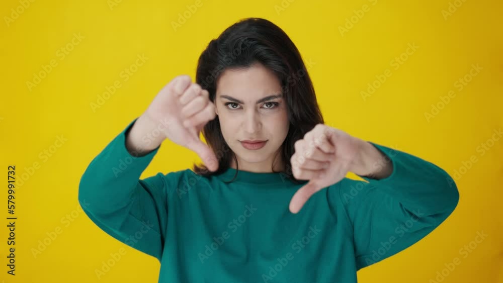 Video of beautiful woman shows diapproval sign keeping thumb down isolated on yellow Video of beautiful woman shows diapproval sign keeping thumb down isolated on yellow
