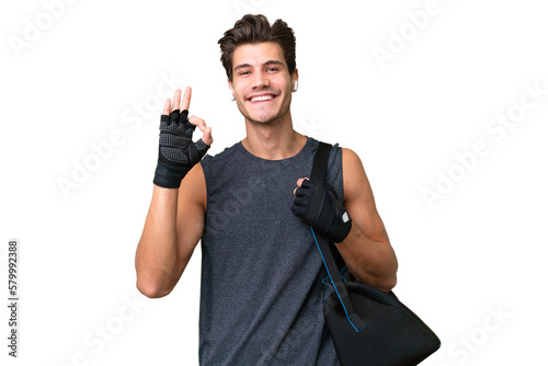 Fototapeta Naklejka Na Ścianę i Meble -  Young sport caucasian man with sport bag over over isolated background showing ok sign with fingers