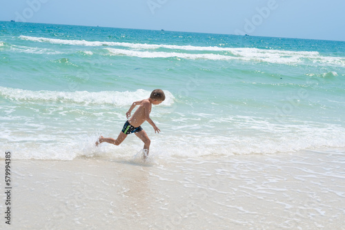 happy boy running on the waves of the sea 