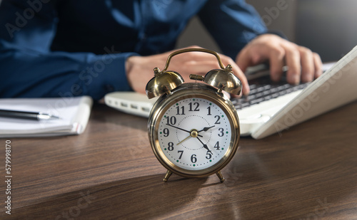 Businessman working at office with a alarm clock on the table.