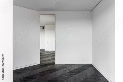 Fototapeta Naklejka Na Ścianę i Meble -  Empty room with dark wooden floating laminate flooring. House interior, wide bedroom or living room space. Newly recently painted new apartment or house. Wood floor. Real estate or property management