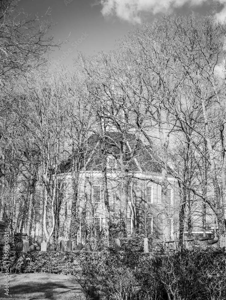 Old cemetery and protestant church behind the trees black and white
