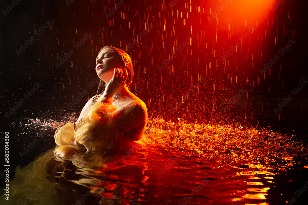 Sexy beautiful woman posing in the rain in aqua studio.