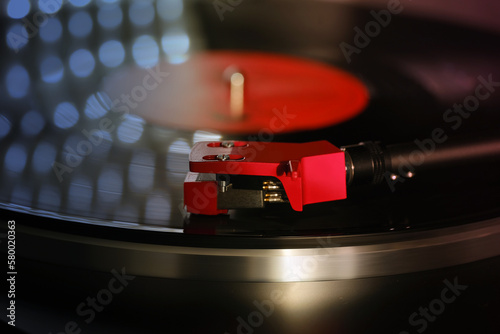 close-up of pickup head on vinyl record, color illumination, analogue retro music concept, hobby of collecting vinyl music discs, audio experience, relaxation, musical enjoyment, vintage technology photo