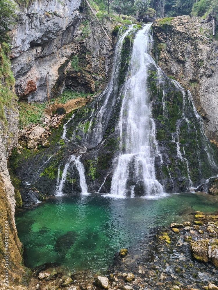 Fototapeta premium Waterfall cascading in green pond, Gollinger waterfall in Golling near Salzburg, Austria. Stunning view of cascade waterfall over mossy rocks in the Alps with long exposure