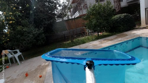 Pool maintenance process. The skimmer net captures fallen leaves and debris from the pool. Cleaning the pool with a skimmer net. Underwater POV shooting of the pool