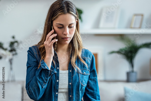 Fotografie Beautiful young woman talking on the phone at home.