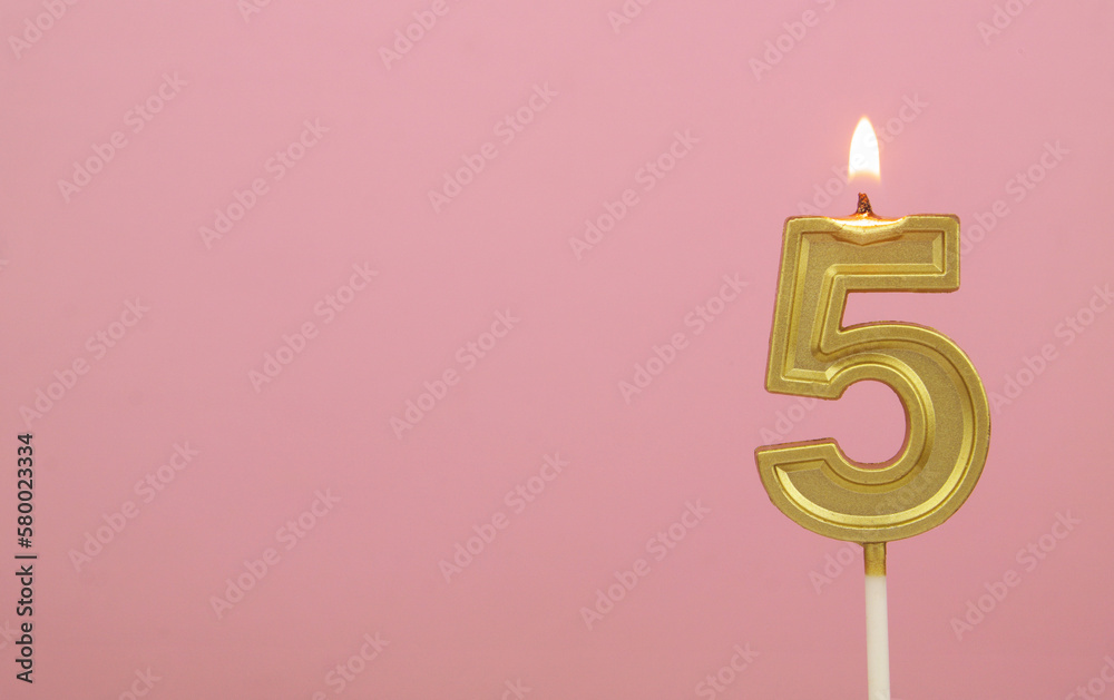 Burning gold birthday candle on pink background, number 5. Large copy space for text. Burning gold birthday candle on pink background, number 5. Large copy space for text.