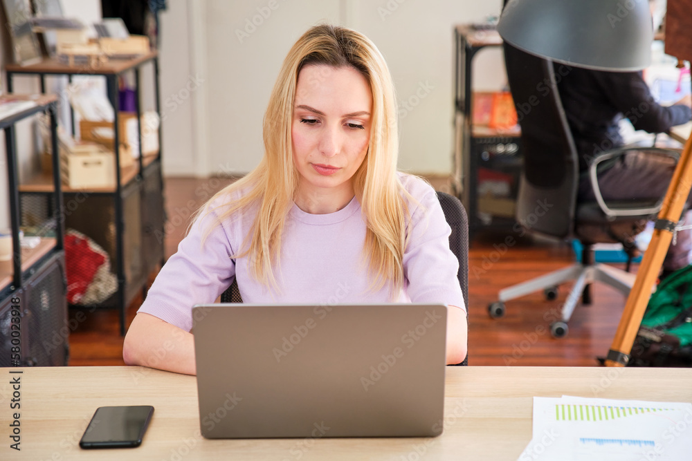 long-haired blonde pretty girl working with a laptop in an office
