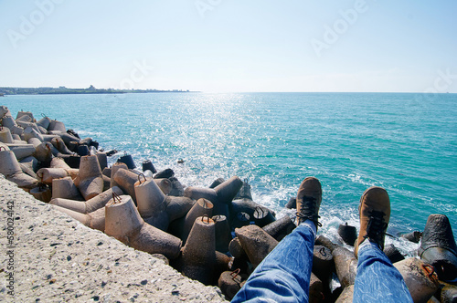Man sitting on the breakwater pier made of concrete tetrapods.