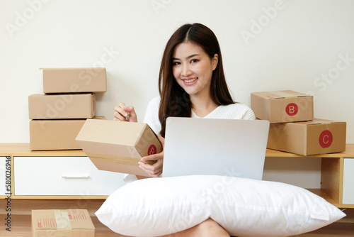 Starting small businesses SME owners female entrepreneurs Use a laptop or notebook to receive and review orders online to prepare to pack boxes, sell to customers, SME online business ideas.