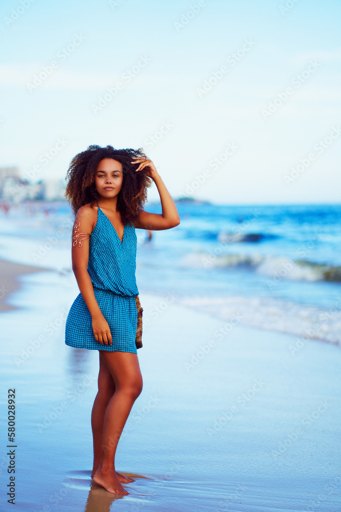 full body portrait beautiful young black brazilian woman standing on the shore of the beach in Ipanema, Rio de Janeiro full body portrait beautiful young black brazilian woman standing on the shore of the beach in Ipanema, Rio de Janeiro