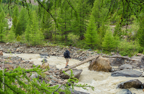 one hiker men crossing river 