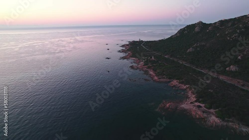 Drone flying over scenic seaside road towards a house on the edge of the shore surraunded by green hills and trees photo