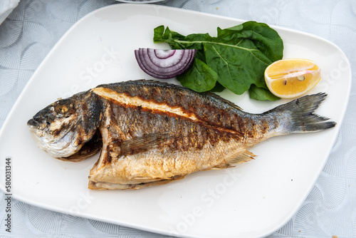 Plate of sea bream fish with French fries and salad in Turkey. photo