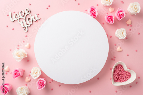 Mother's Day celebration concept. Top view photo of white circle small roses inscription love you and heart shaped saucer with sprinkles on isolated pastel pink background with copyspace