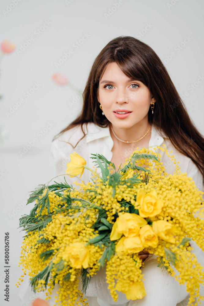 beautiful gentle woman brunette with a bouquet of yellow tulips and mimosa beautiful gentle woman brunette with a bouquet of yellow tulips and mimosa