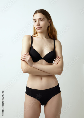 beautiful woman posing in a black swimsuit on a light background