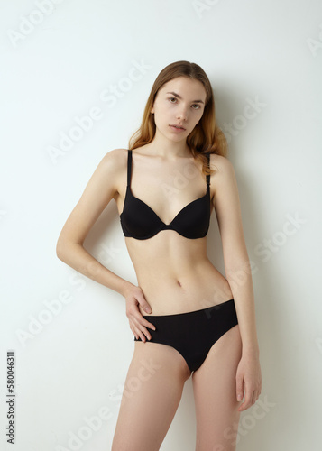 beautiful woman posing in a black swimsuit on a light background © Lina Solntseva 