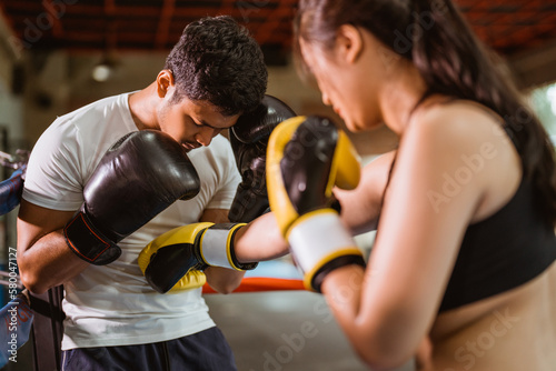 a female boxer punching the male boxer on his stomach while fighting inside the box ring