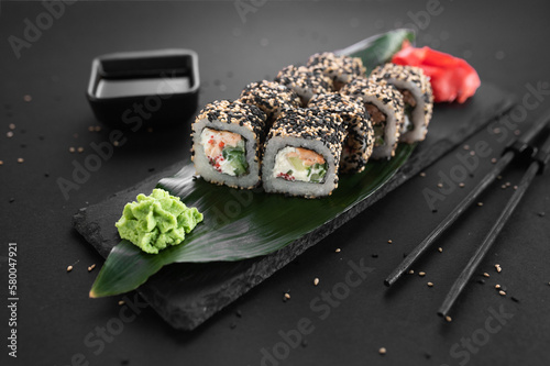 California sake roll with salmon, avocado and sesame. Traditional Japanese cuisine, sushi rolls on a black background photo