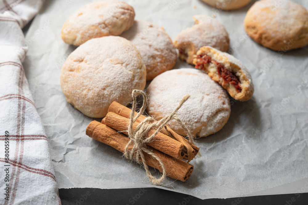 Fototapeta premium Round apple cookies and string tied cinnamon sticks on greaseproof baking paper