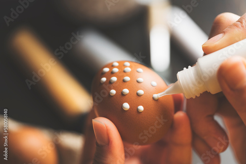 DIY handpainted easter eggs. Hand pianting white dots on brown egg. photo