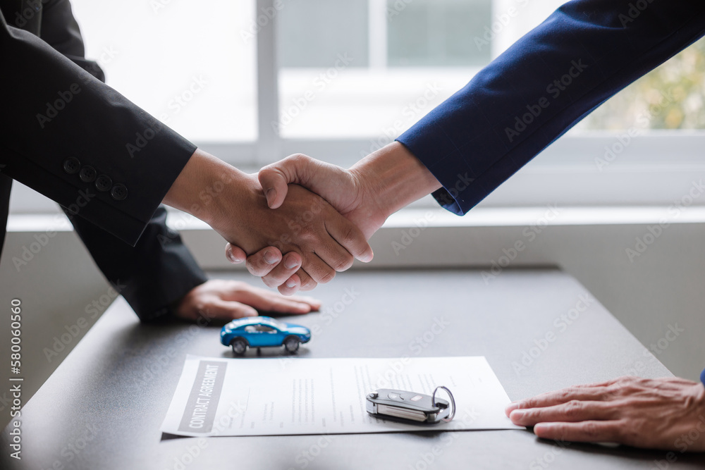 Two businessmen shaking hands to end a meeting Mature man signing a contract in the showroom office. trading ideas business partner.