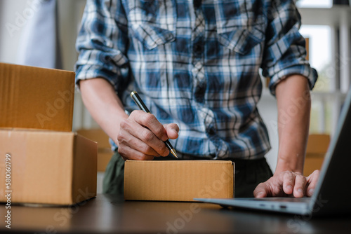 Small business entrepreneur, SME, freelance male working with boxes at home. Use a laptop for commercial auditing. online marketing Packaging Box SME Seller Concept Ecommerce Team online sales
