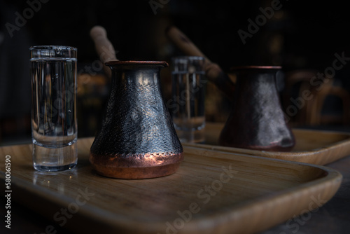 Coffee cezve on a table in dark cafe with a glass of water