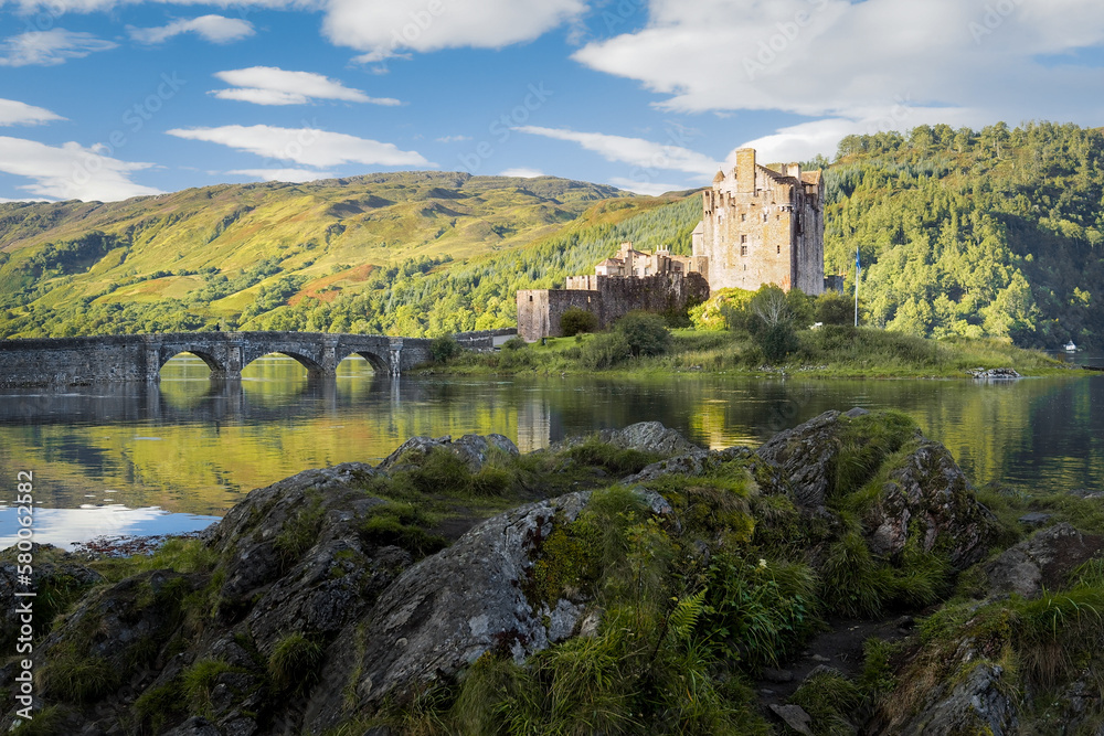 Obraz premium Eilean Donan castle in a golden hour light of early morning. Medieval Scottish castle reflecting in the water on a nice summer day. Castle in Scottish highlands. Cultural heritage of Scotland.