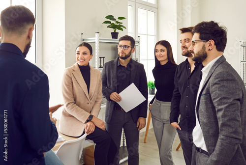 Group of business people chatting after a meeting. Company employees talking in the office. Making great decisions with brainstorming. Cowokers listen to their colleague at the working place. photo