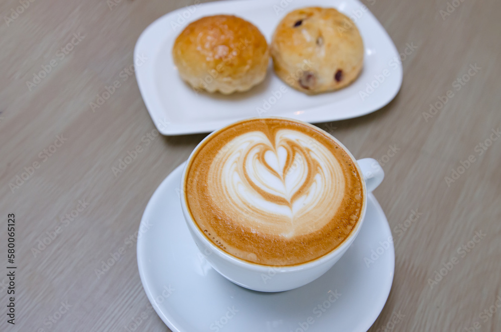 A wooden table with a fragrant cappuccino and baked bread