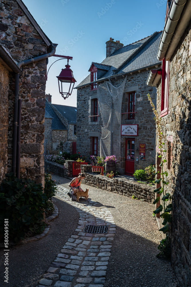 Young Woman Pets A Red Cat In The Breton Village Saint Suliac In Department Ille et Vilaine In Brittany, France
