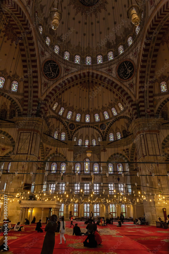 Interior of Fatih Mosque, Ottoman mosque in the Fatih district of Istanbul, with a huge decorated domes. Arabic text as decor (verses from Koran, muslim Holy book). Vertical shot. Istanbul, Turkey